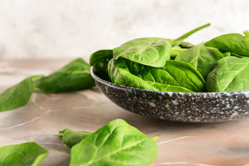 Plate with fresh spinach on table