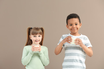 Cute little children with glasses of milk on color background