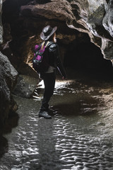 Girl exploring huge cave. Adventure traveller dressed cowboy hat and backpack, leather jacket. extreme vacation, tourist route. ancient crystal formations, vertical photo, village Kryvche. Ukraine