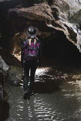 Girl exploring huge cave. Adventure traveller dressed cowboy hat and backpack, leather jacket....