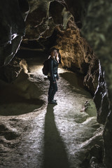 Silhouette Girl exploring huge cave. Adventure traveller dressed cowboy hat and backpack, leather jacket. vertical photo, tourist route. ancient crystal formations, geology, village Kryvche. Ukraine