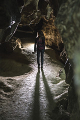 Silhouette Girl exploring huge cave. Adventure traveller dressed cowboy hat and backpack, leather...