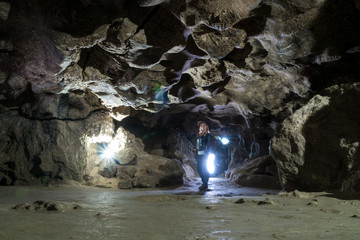 Girl exploring huge cave. Adventure traveller dressed cowboy hat and backpack, leather jacket. extreme vacation, tourist route. ancient crystal formations, geology, village Kryvche. Ukraine