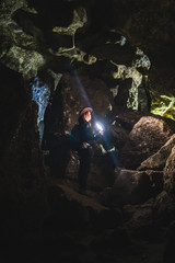 Obraz premium Girl exploring huge cave. Adventure traveller dressed cowboy hat and backpack, leather jacket. extreme vacation, tourist route. ancient crystal formations, vertical photo, village Kryvche. Ukraine
