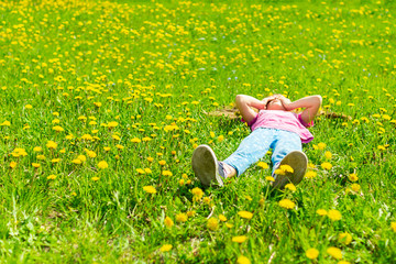 Little girl is lying on the green meadow in fresh grass. Summer concept. Selective focus. Copy space. View from above