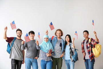 Group of students with USA flags on light background - obrazy, fototapety, plakaty