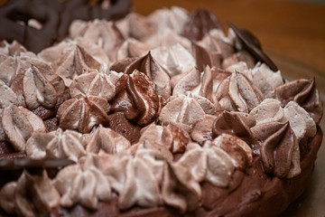 layers of frosting swirled on top of a thin single layer coffee flavored cake on a platter set on a table in a kitchen