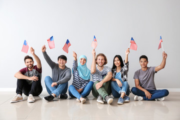 Group of students with USA flags sitting near light wall