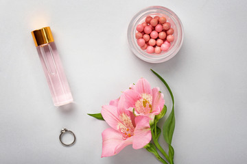 Decorative cosmetics and flowers on light background