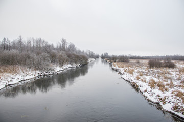Winter landscape on the river. Snow picture. Snow and river. Cloudy snow day.