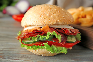Tasty burger with bacon on table