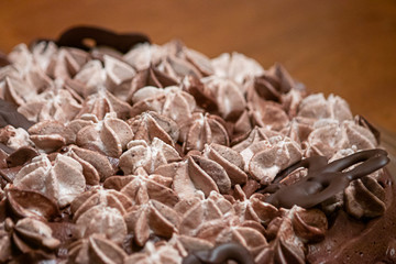 layers of varigated frosting swirled on top of a thin single layer coffee flavored cake set on a table in a kitchen