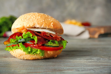 Tasty burger with bacon on table
