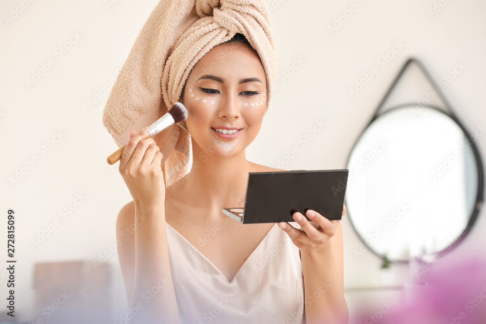 Poster Asian woman applying contouring makeup at home