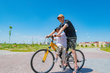 Fototapeta premium Older and younger brothers ride a bike
