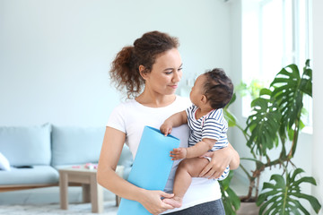 Sporty African-American woman with cute little baby at home