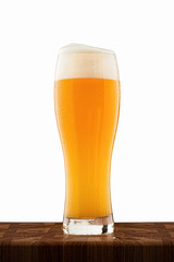 misted full cup of cold beer on a wooden table isolated on white background