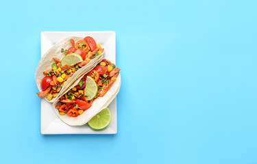 Plate with tasty tacos on color background