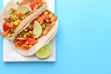 Plate with tasty tacos on color background