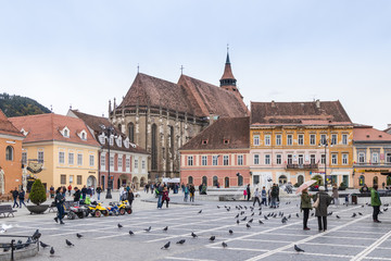 Tourists walk in the Square of Council Market around the Historical Museum and see the sights in the Old Town of Brasov in Romania