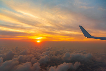 Wing of the air plane on the sea of cloud sunset sky background from window airplane