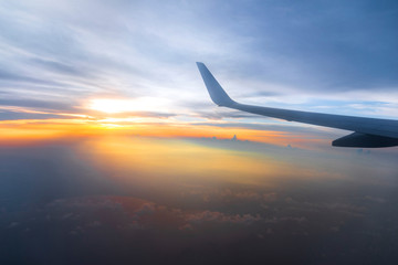 Fototapeta na wymiar Wing of the air plane on the sea of cloud sunset sky background from window airplane
