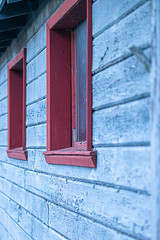 old building with blue wooden siding and red trim aged and distressed from time