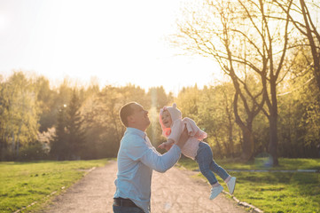 Happy family together, parents with their little child at sunset. Father raising baby up in the air. Father's day concept