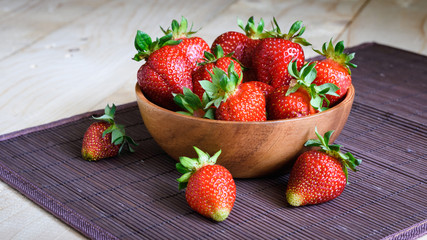 strawberries in a wooden bowl on a wooden background