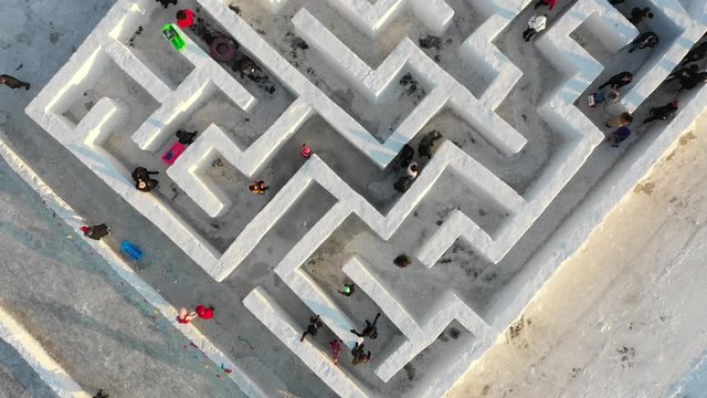 Slow drone shot of people walking through snow maze during the Harbin International Ice and Snow Sculpture Festival, Winter entertainment in China