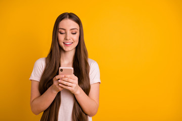 Close up photo beautiful amazing she her lady very long hairstyle wondered hold hands arms telephone read romantic letters boyfriend wear casual pastel t-shirt isolated yellow bright background