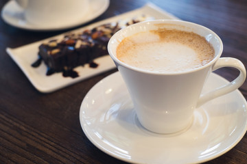 Latte coffee and brownie cake on wooden table in the cafe.
