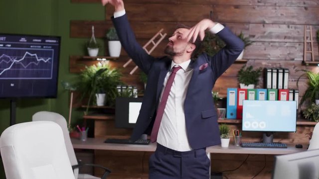 Slow motion handheld shot of corporate office worker dancing while nobody else is watching