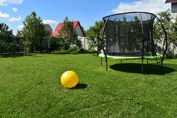 Trampoline on the lawn with a yellow ball..