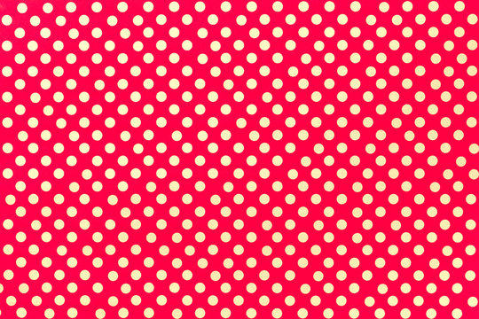 Bright red background from wrapping paper with a pattern of golden polka dot closeup.