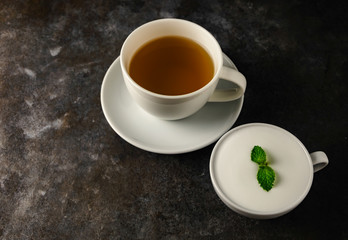 tea in a white cup and mint on a rough brown texture