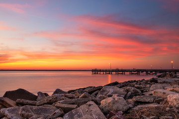 Vibrant pink and orange sunset over a fishing pier and rock jetty. Jones Beach New York. 