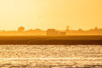 Golden light shining on a small bay house on the water at sunset. Long Island New York. 