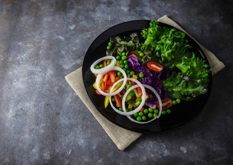 vegetable salad in a black plate on rough brown texture and sack