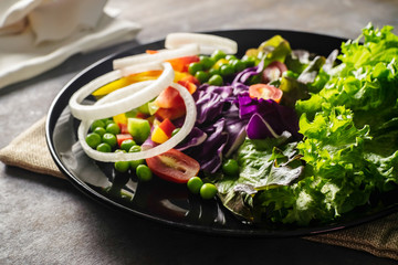 vegetable salad in a black plate on rough brown texture and sack