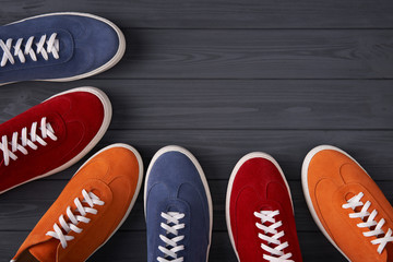 Colorful suede sneakers forming a frame with copy space, on grey wooden planks