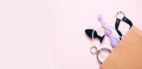 Adult sex toys and accessories purchases on pink background. Anal dildo, butt plug in paper bag....