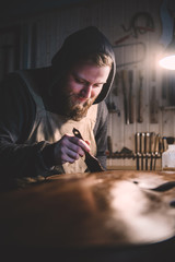 Obraz premium Young luthier working in his workshop, building a double bass