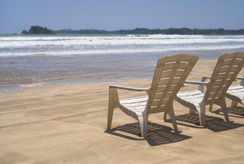 Beautiful Sri Lankan view of the Indian Ocean with sun loungers on the beach. Summer holidays in Asia. Stock photos