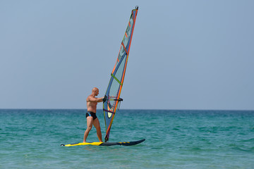 Sports man Windsurfing at sea on a Sunny summer day.