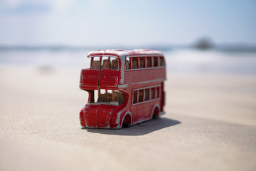 Red toy bus in nature pollutes the earth's ecosystem. English bus without wheels. Consumer world...