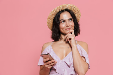 Young happy woman posing isolated over pink wall background using mobile phone.