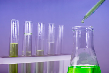 Sample dripping pipettes into Erlenmeyer bottles containing chemical green, background, close