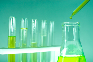 Sample dripping pipettes into Erlenmeyer bottles containing chemical green, background, close
