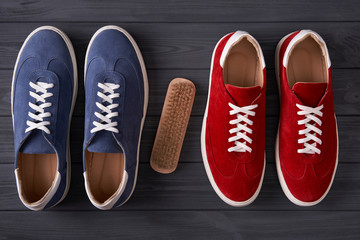 Top view of red and blue casual unisex suede sneakers with cleaning brush